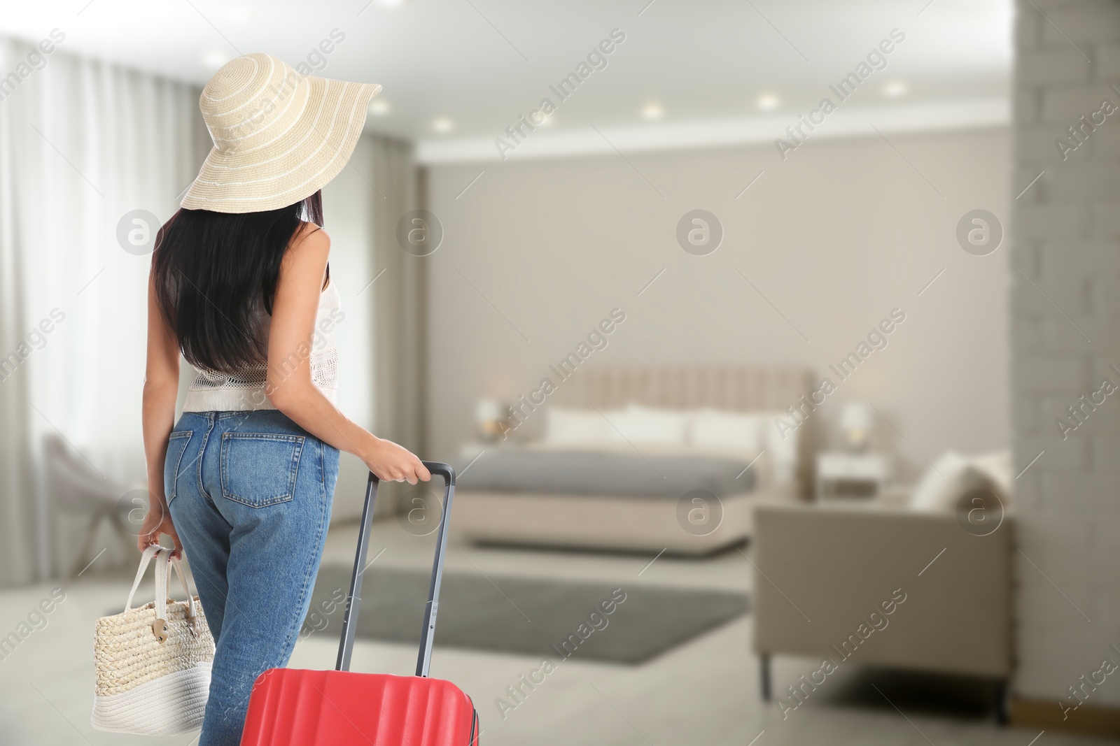 Image of Woman with suitcase and bag in hotel room