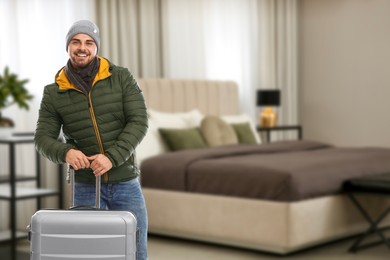 Image of Happy man with suitcase in hotel room
