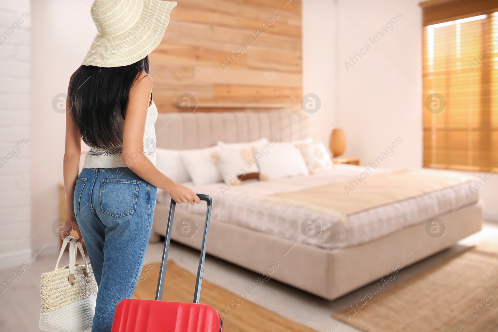 Image of Woman with suitcase and bag in hotel room. Guest heading to bed