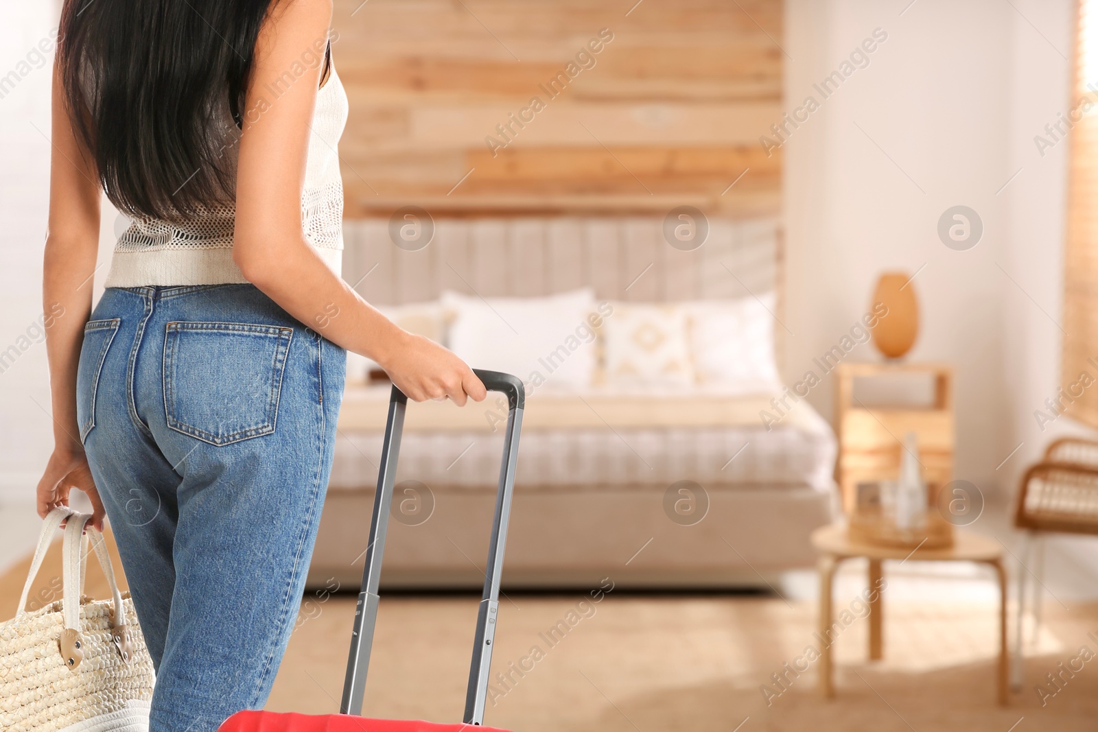 Image of Woman with suitcase and bag in hotel room, closeup. Guest heading to bed