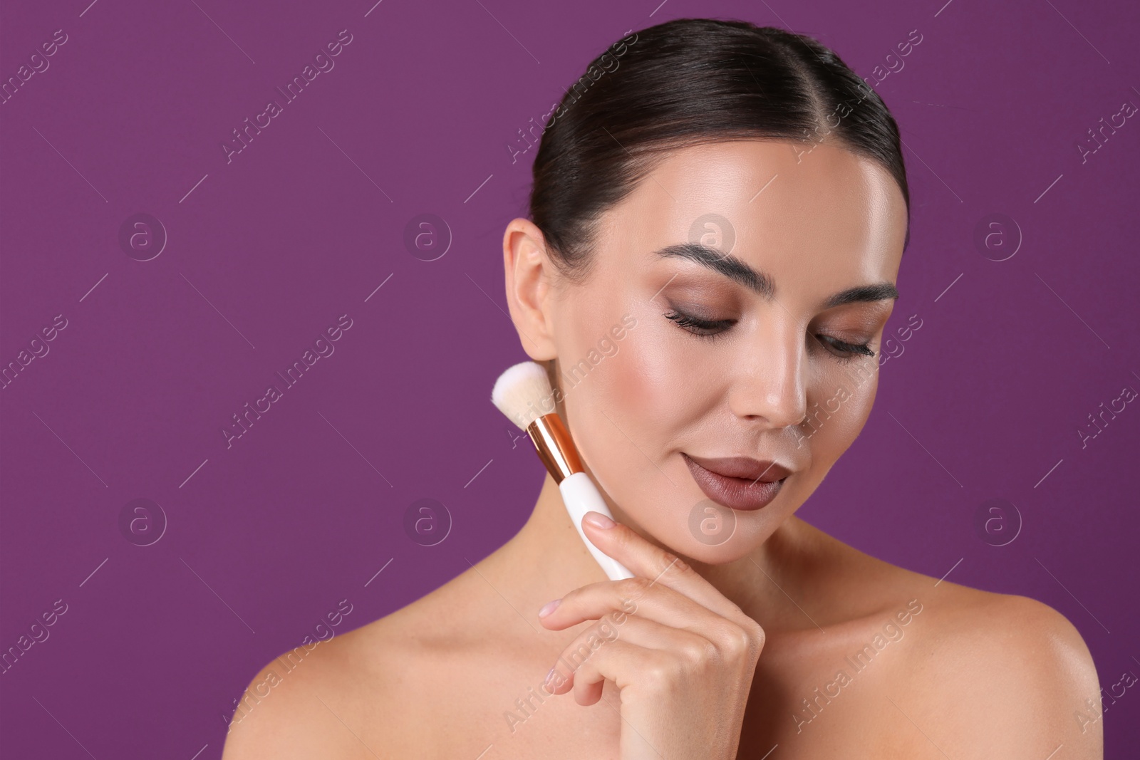 Image of Beautiful woman with makeup brush on purple background
