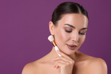Image of Beautiful woman with makeup brush on purple background