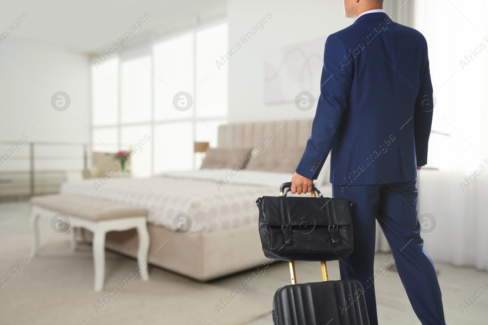 Image of Businessman with suitcase and bag in hotel room. Guest heading to bed