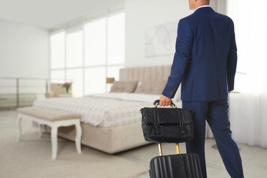 Image of Businessman with suitcase and bag in hotel room. Guest heading to bed