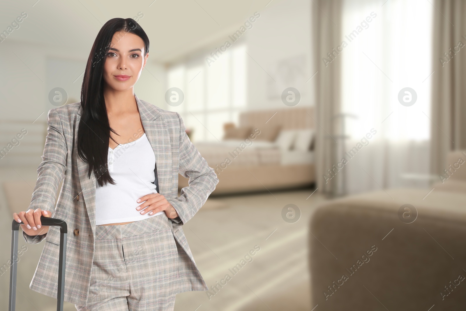 Image of Business woman with suitcase in hotel room