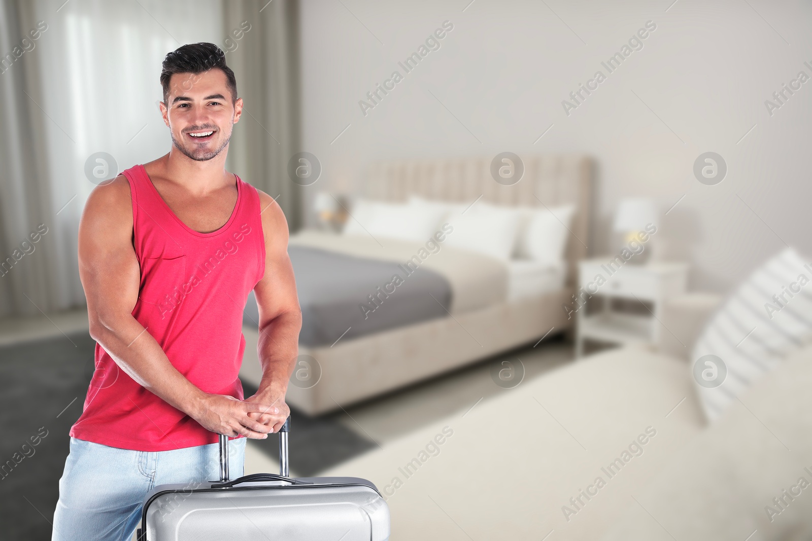 Image of Happy man with suitcase in hotel room