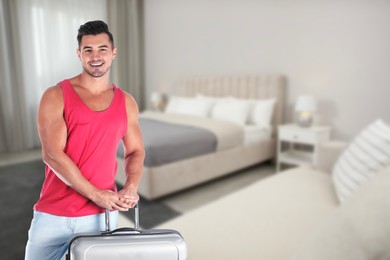 Image of Happy man with suitcase in hotel room