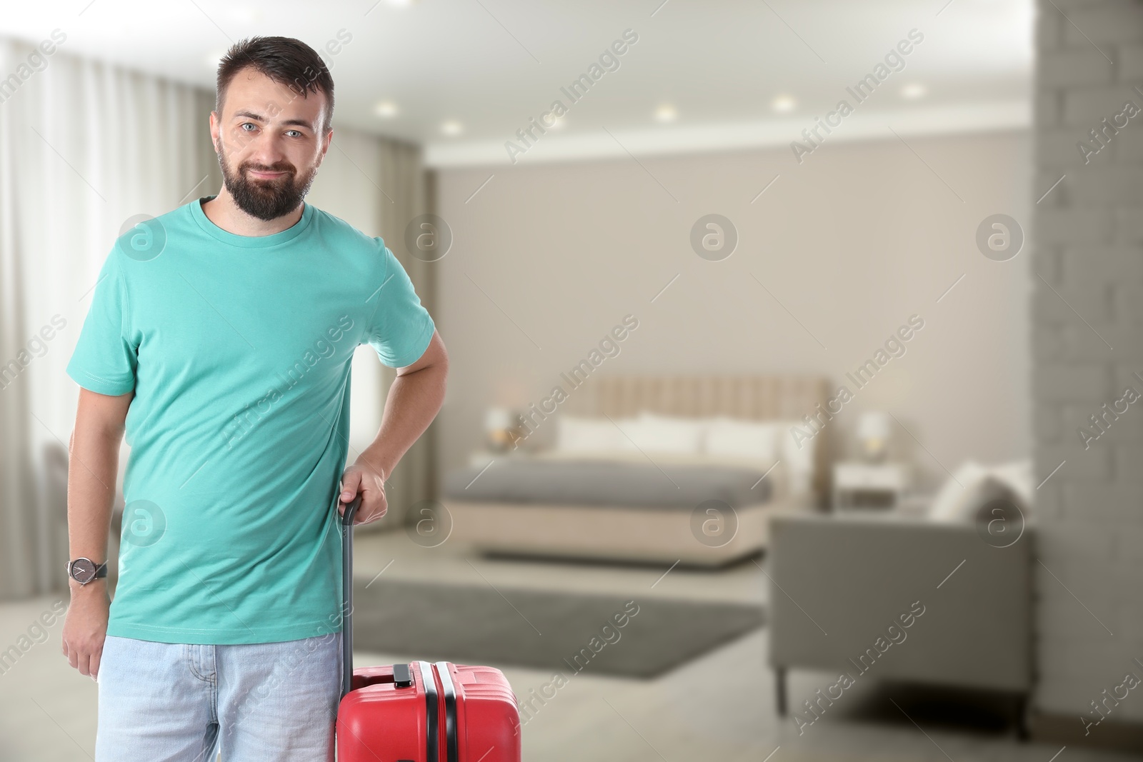 Man with red suitcase in hotel room Image of Man with red suitcase in hotel room