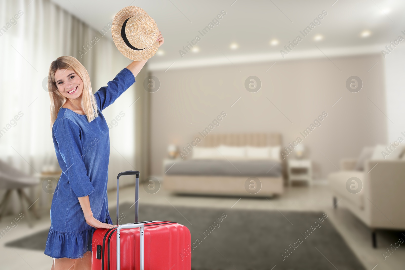 Image of Happy woman with suitcases in hotel room