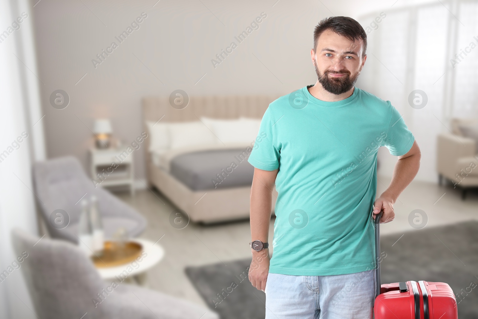 Man with red suitcase in hotel room Image of Man with red suitcase in hotel room
