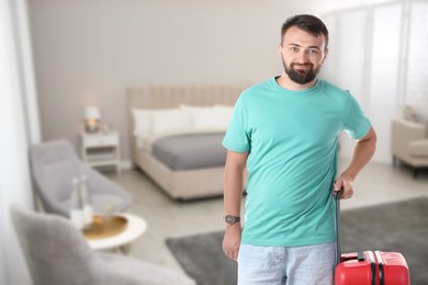 Image of Man with red suitcase in hotel room