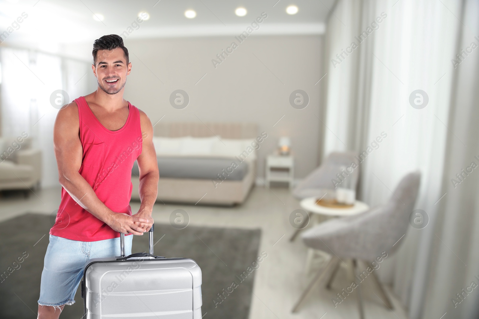 Image of Happy man with suitcase in hotel room