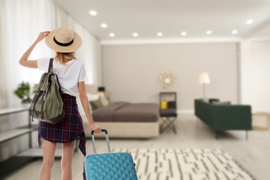 Image of Woman with suitcase and backpack in hotel room, back view