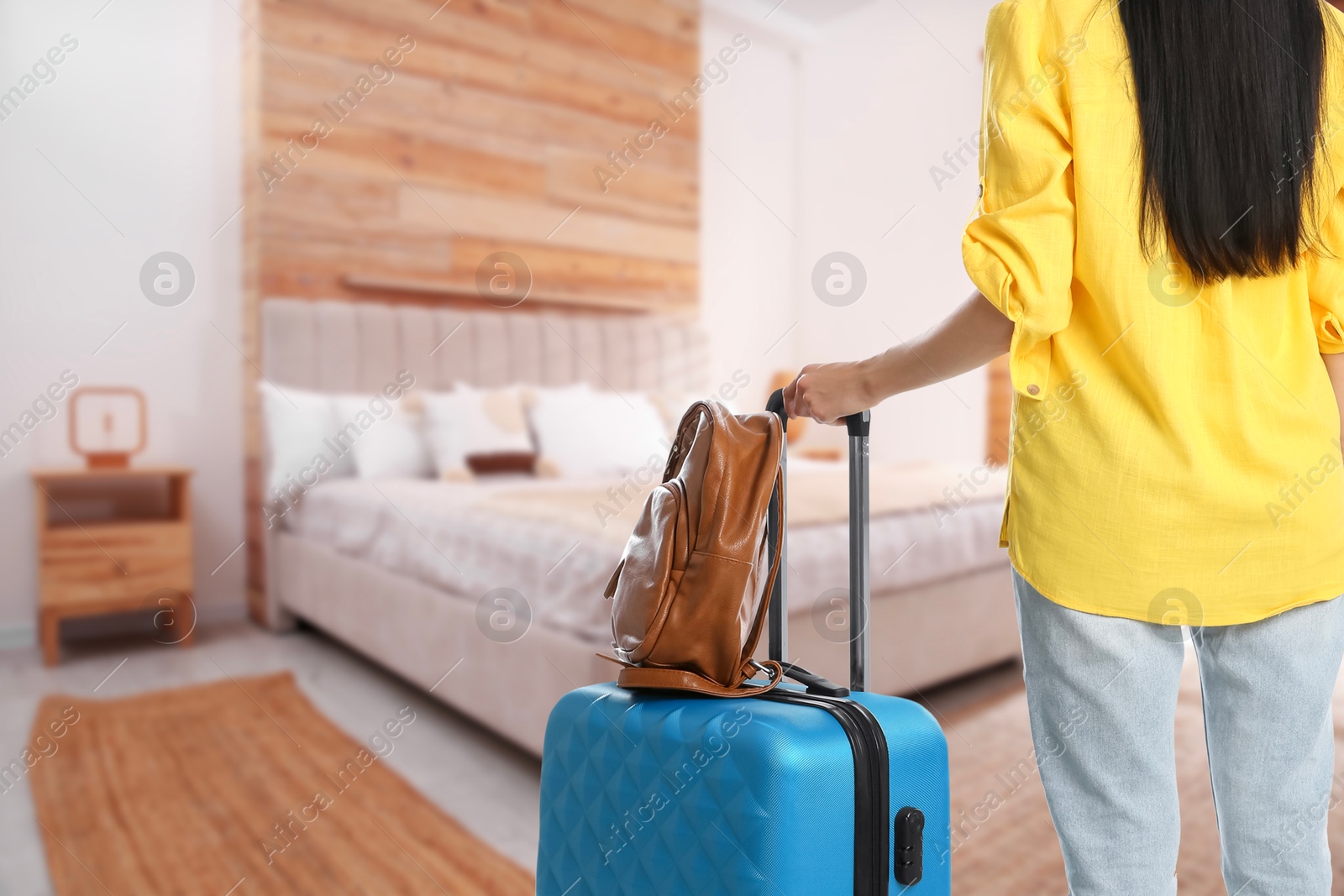 Image of Woman with suitcase and backpack in hotel room, closeup