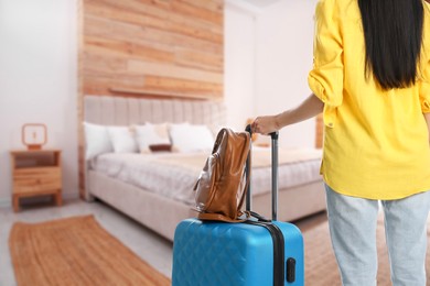 Image of Woman with suitcase and backpack in hotel room, closeup