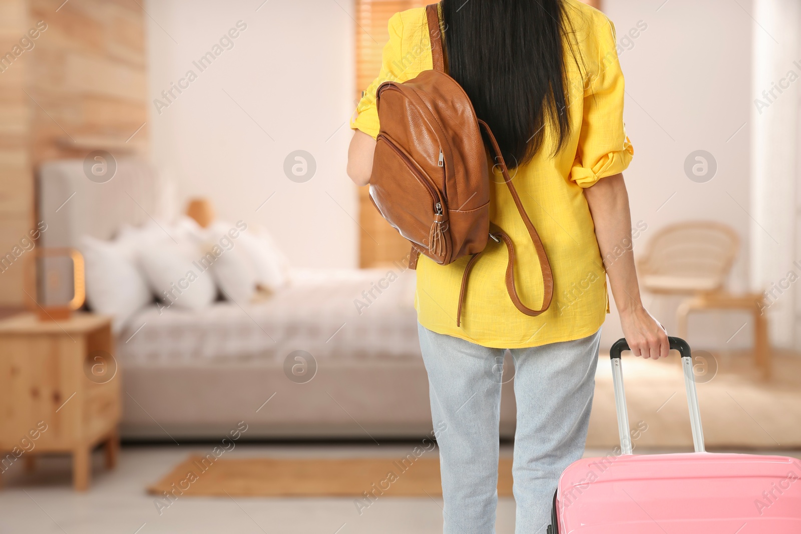 Image of Woman with suitcase and backpack in hotel room, closeup