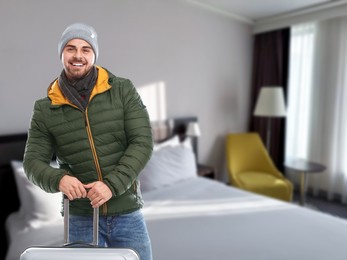 Image of Happy man with suitcase in hotel room