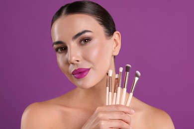 Image of Beautiful woman with makeup brushes on purple background