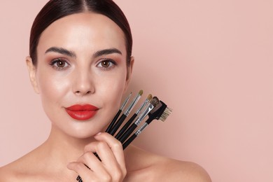 Image of Beautiful woman with makeup brushes on pink beige background