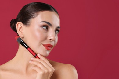 Image of Beautiful woman with makeup brush on crimson color background