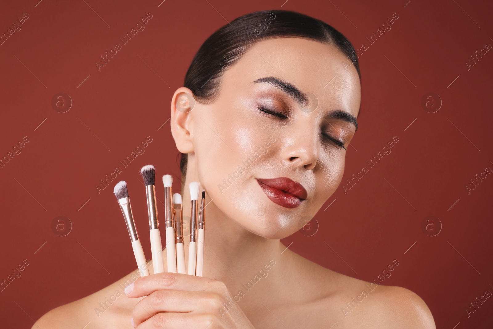 Image of Beautiful woman with makeup brushes on red brown background