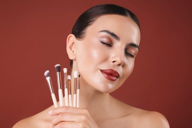 Image of Beautiful woman with makeup brushes on red brown background