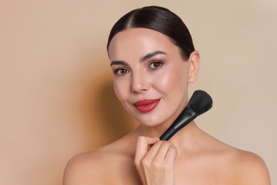 Image of Beautiful woman with makeup brush on beige background