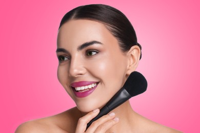 Image of Beautiful woman with makeup brush on bright pink background