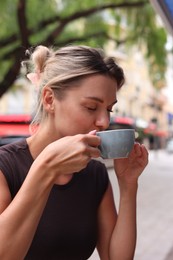 Photo of Beautiful young woman with cup of coffee outdoors