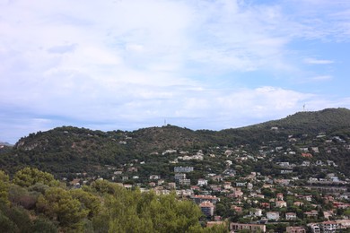 Photo of Picturesque view of city with buildings and trees in mountains