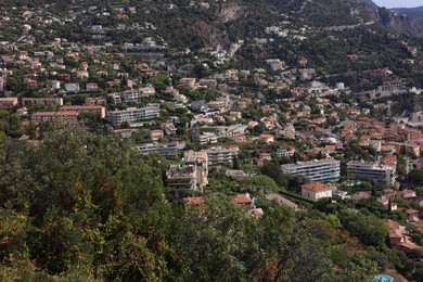 Photo of Picturesque view of city with buildings and trees in mountains