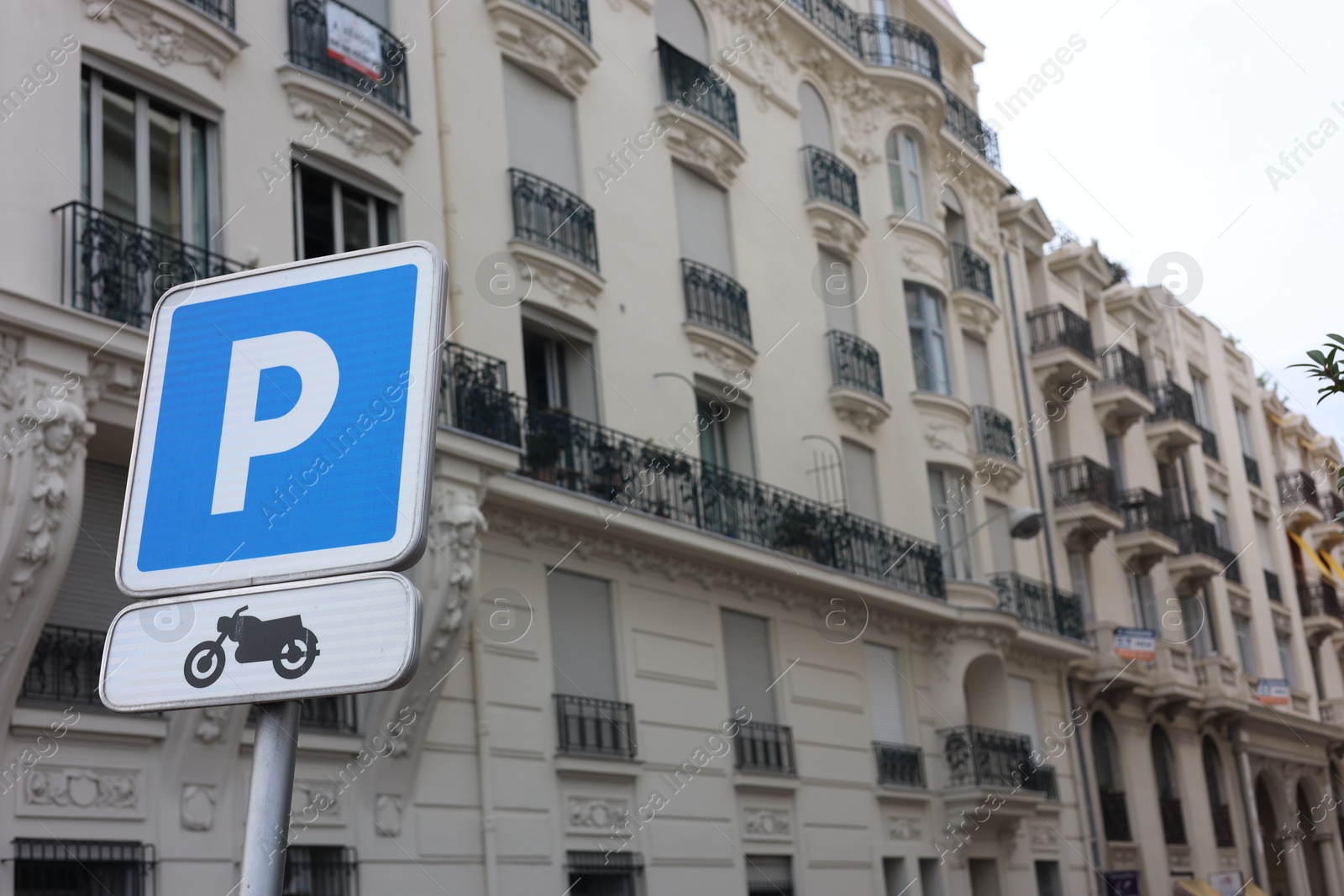 Photo of Motorcycle parking sign and beautiful building on city street, low angle view