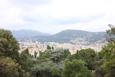 Photo of Picturesque view of cityscape with buildings, green trees and mountains