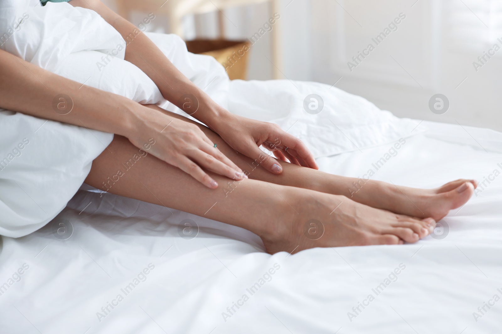 Photo of Woman covering with blanket on bed at home, closeup