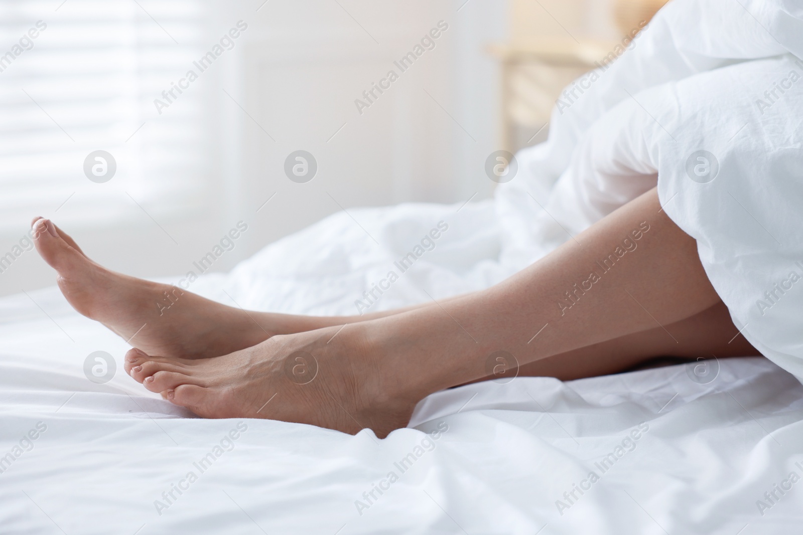 Photo of Woman covering with blanket on bed at home, closeup