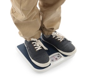 Photo of Boy standing on scales against white background, closeup
