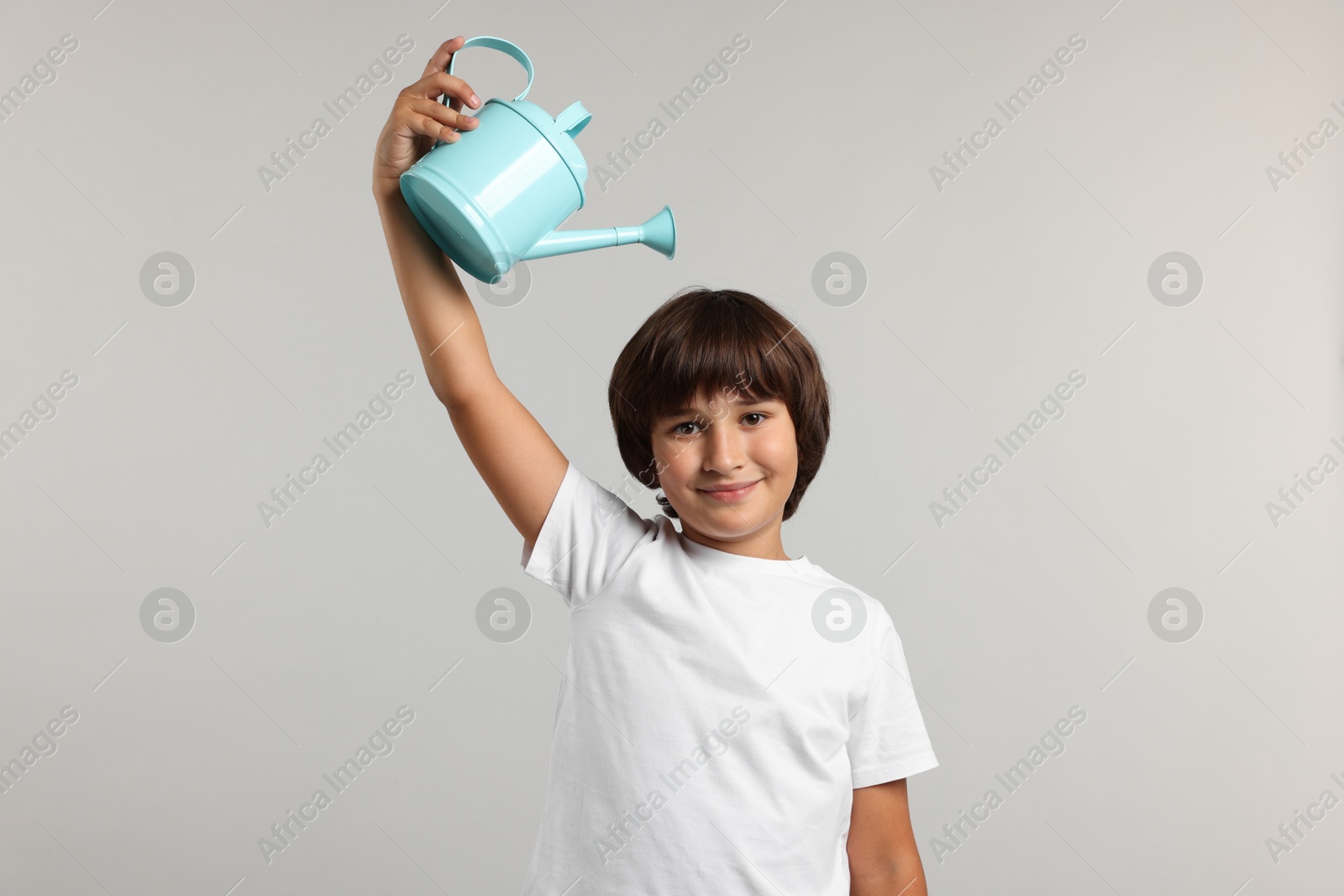 Photo of Little boy with watering can on grey background. Grow up faster