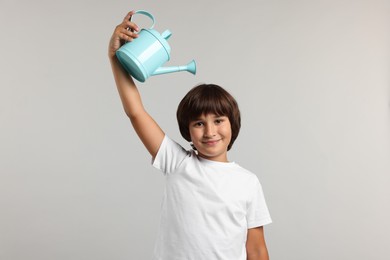 Photo of Little boy with watering can on grey background. Grow up faster