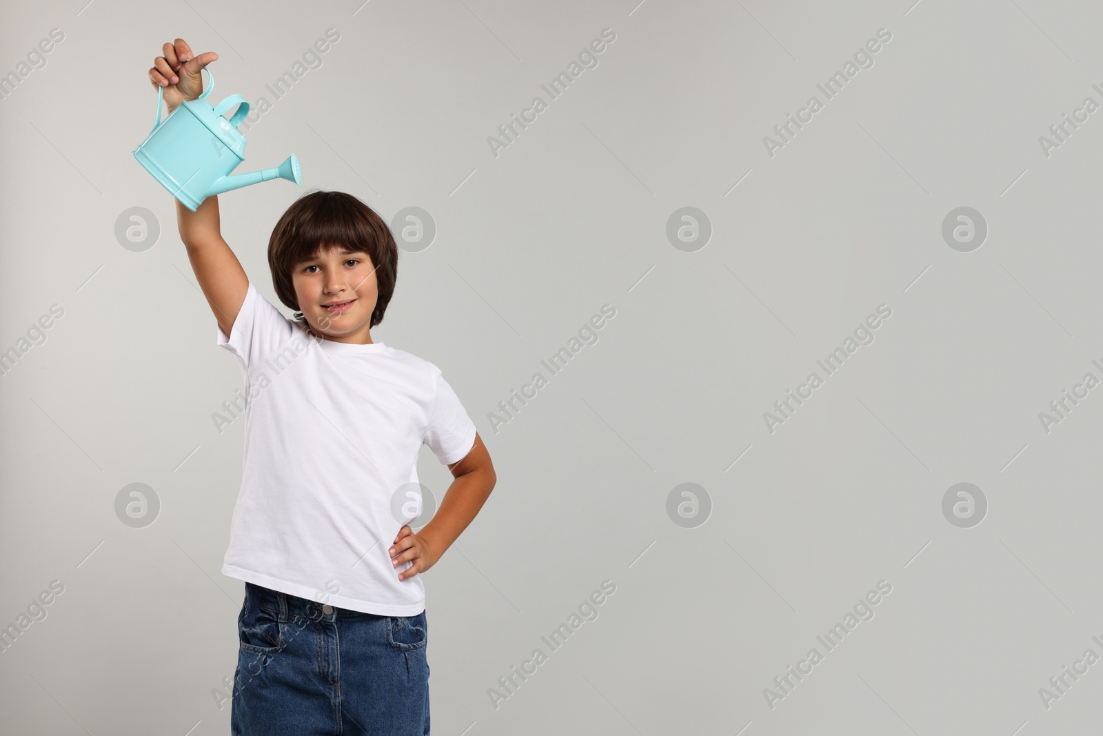 Photo of Little boy with watering can on grey background, space for text. Grow up faster