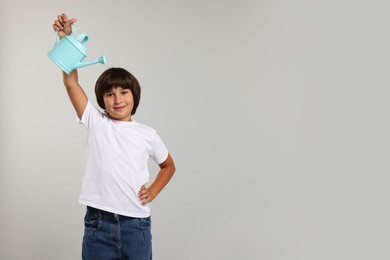 Photo of Little boy with watering can on grey background, space for text. Grow up faster