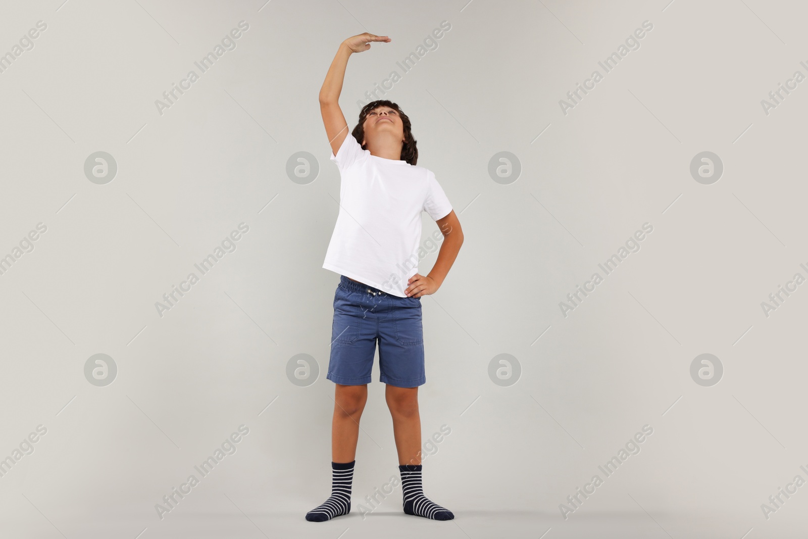 Photo of Little boy measuring his height on grey background