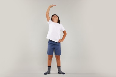 Photo of Little boy measuring his height on grey background