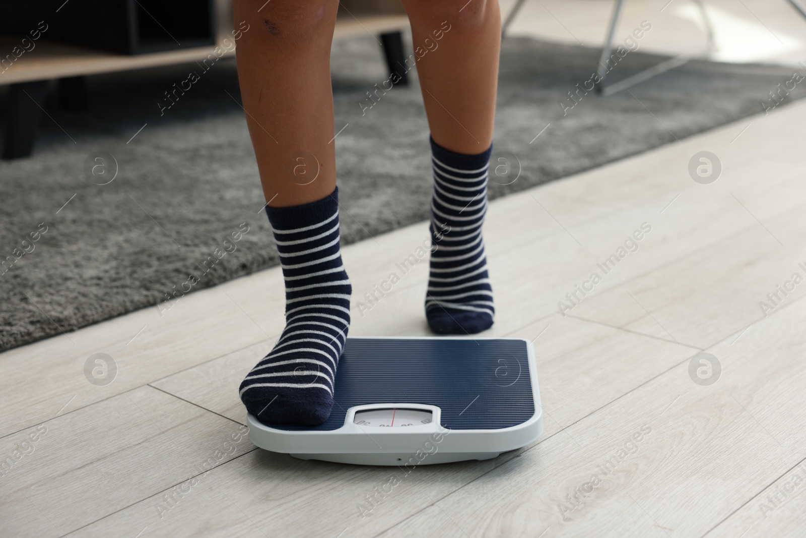 Photo of Little boy standing on scales indoors, closeup