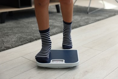 Photo of Little boy standing on scales indoors, closeup