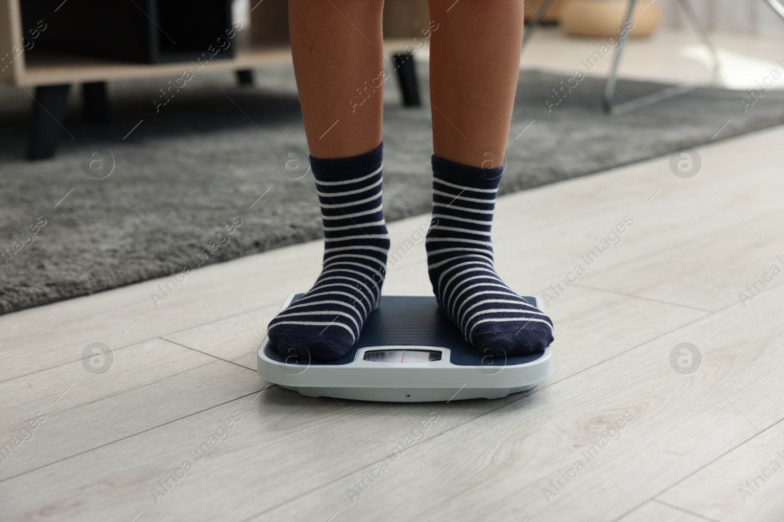 Photo of Little boy standing on scales indoors, closeup
