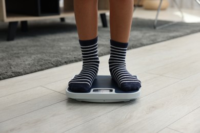 Photo of Little boy standing on scales indoors, closeup