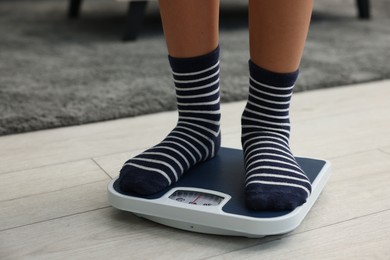 Photo of Little boy standing on scales indoors, closeup