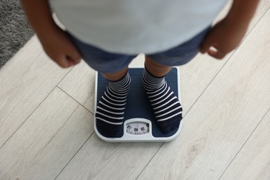 Photo of Little boy standing on scales indoors, top view