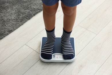 Photo of Little boy standing on scales indoors, closeup