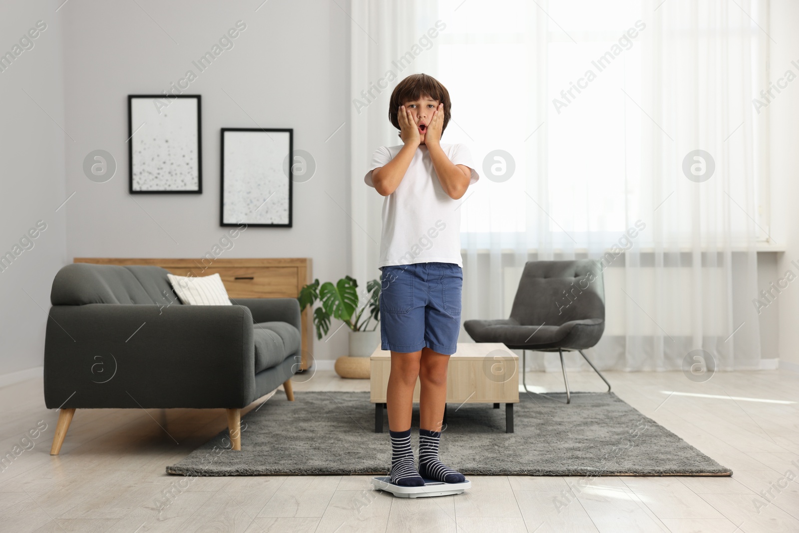 Photo of Emotional boy standing on scales at home